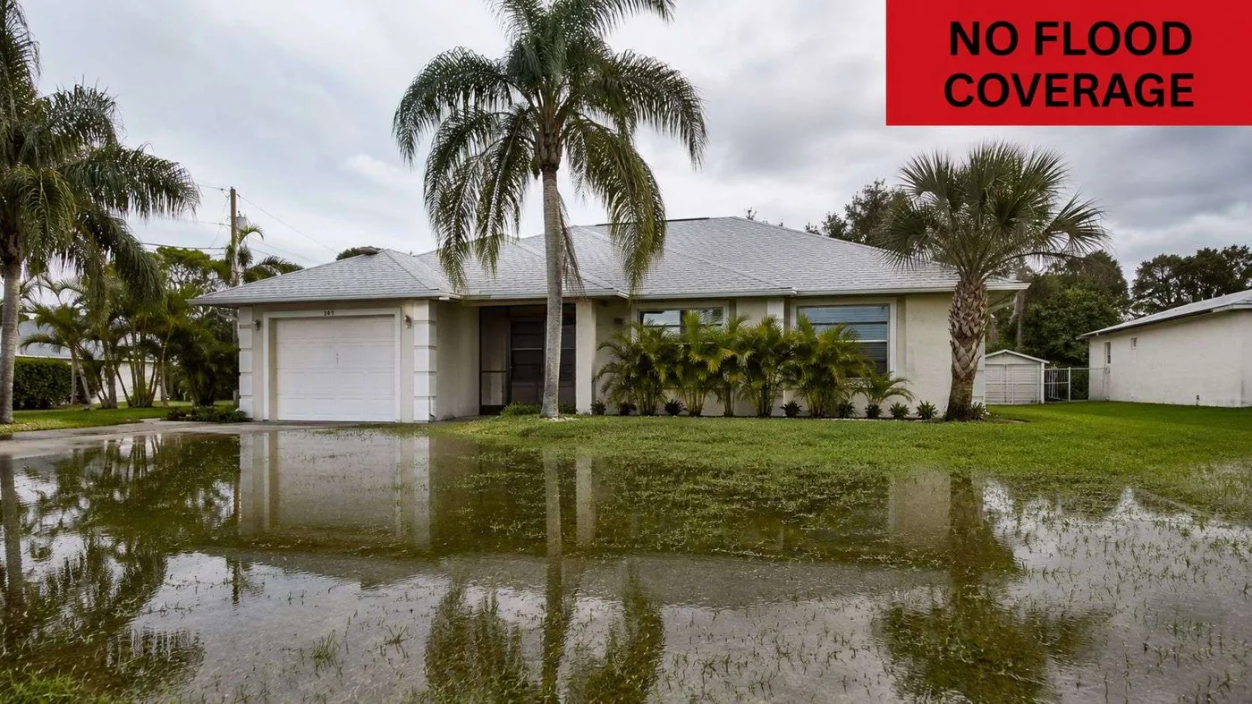 A suburban house in Micco surrounded by standing floodwater on its lawn on a cloudy day.