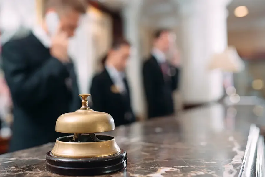Hospitality Insurance Front Desk Associate on the Phone with a Bell on the Desk of a Luxury Hotel Hospitality Insurance Helping you protect homes away from home.