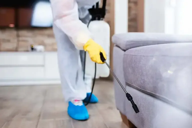 Pest Control Insurance Exterminator in Full Body Work Gear Spraying Pesticide Within a Family Home and Using Sprayer Underneath Furniture 768x512 1 Pest Control Insurance  
